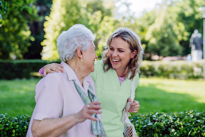 Altenpflegerin mit älterer Frau im Park - Betreuungsleistungen